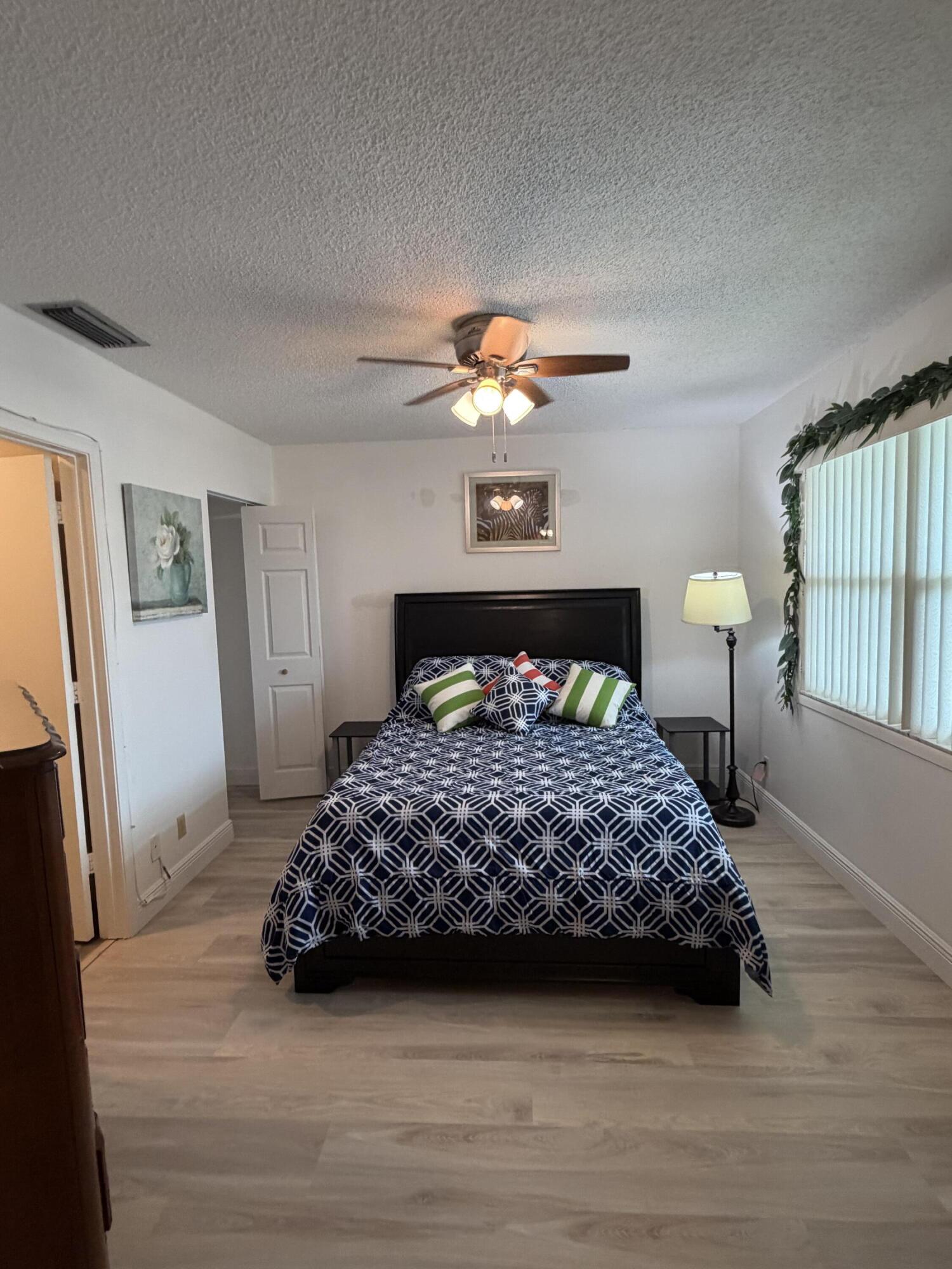1121 Cactus Terrace, Unit 202 Delray Beach, FL 33445 - Photo 8 of 31 a bedroom with a bed and a chandelier