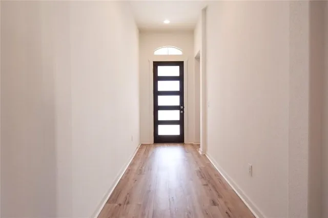 an empty room with wooden floor chandelier fan and windows