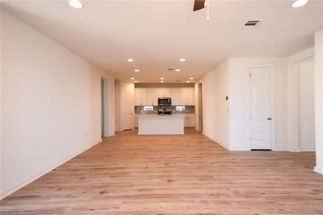 an empty room with wooden floor a ceiling fan and a window