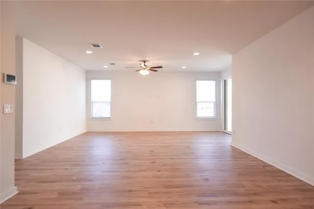 an empty room with a ceiling fan and wooden floor