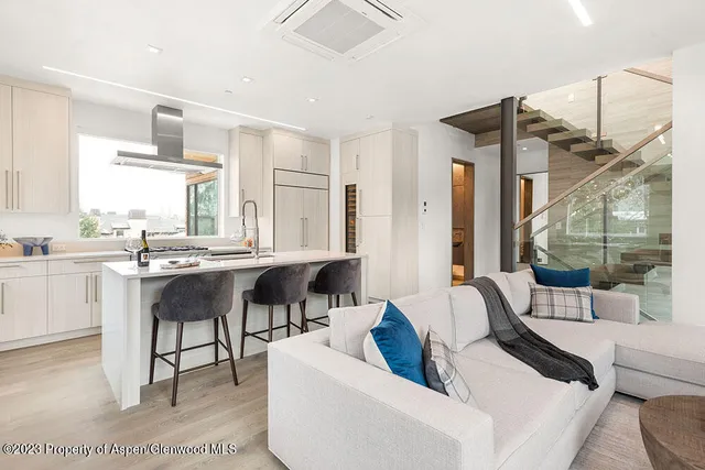 a living room with furniture a large window and kitchen view