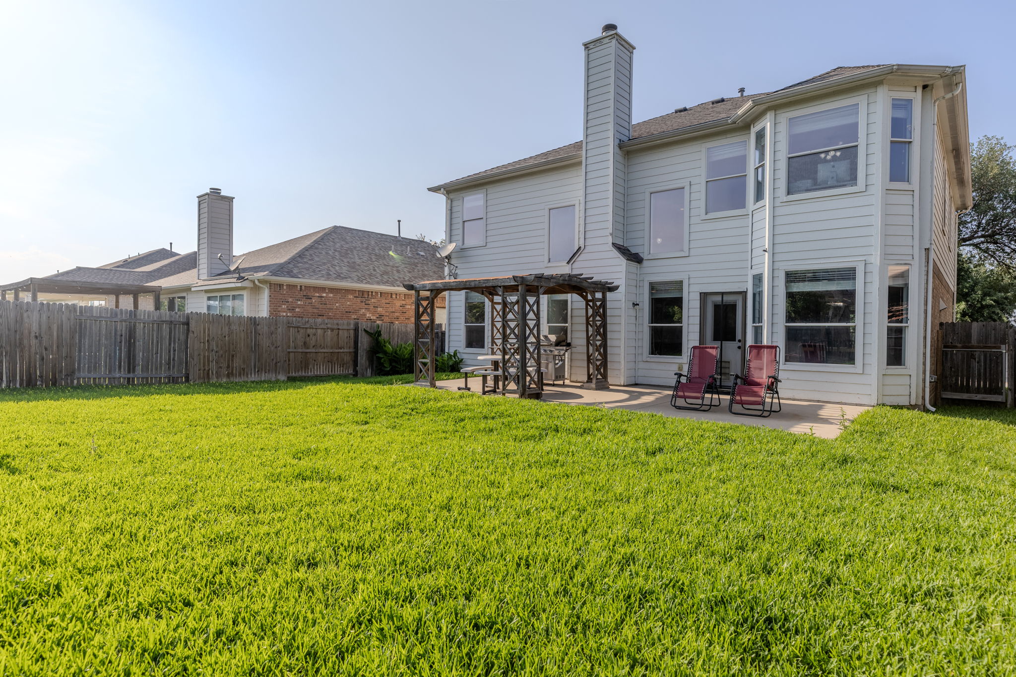 3517 Shiraz Loop Round Rock, TX 78665 - Photo 39 of 40 Expansive rear yard featuring a large green lawn, a concrete patio, and a wooden pergola structure