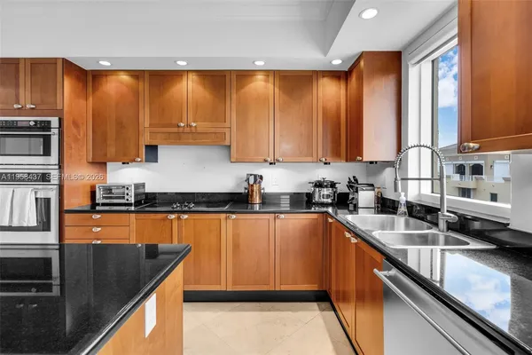 a kitchen with stainless steel appliances granite countertop a sink counter space cabinets a stove and a sink