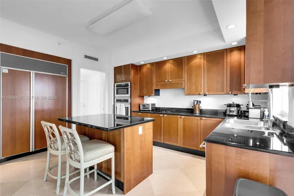 a kitchen with stainless steel appliances granite countertop a stove top oven a sink a dining table and chairs with wooden floor