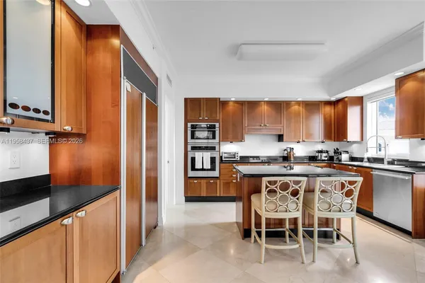 a kitchen with stainless steel appliances granite countertop table chairs sink and window