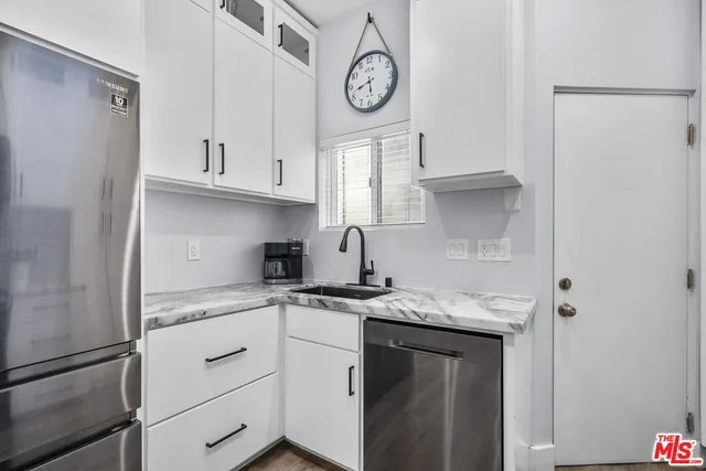 a kitchen with stainless steel appliances granite countertop a sink a stove and a refrigerator with white cabinets