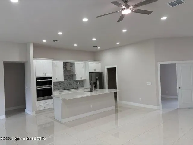 a large kitchen with stainless steel appliances kitchen island a large counter top and oven