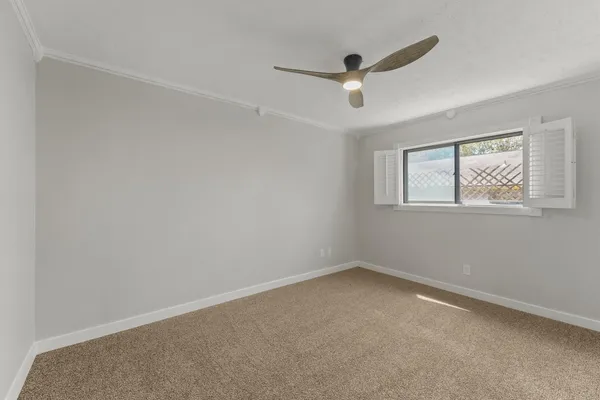 an empty room with a window and a ceiling fan