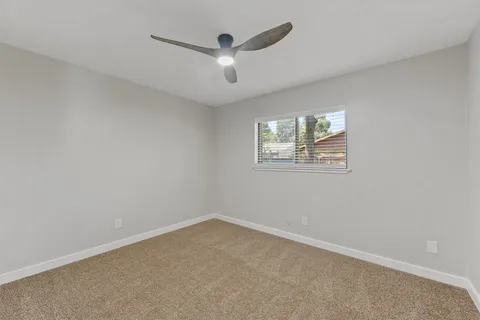 an empty room with a window and a ceiling fan
