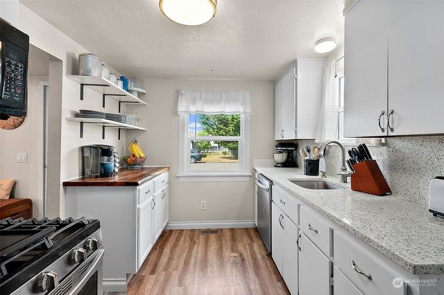 a kitchen with a sink a stove cabinets and a window