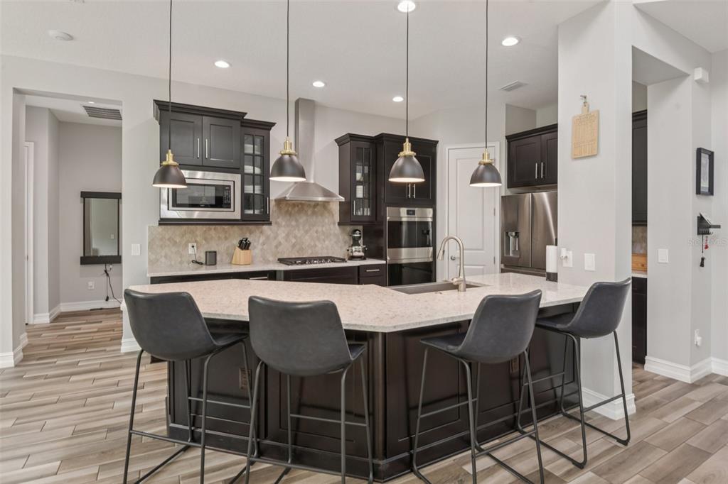 1440 Keystone Ridge Circle Tarpon Springs, FL 34688 - Photo 9 of 45 a kitchen with stainless steel appliances kitchen island granite countertop a dining table chairs refrigerator and microwave