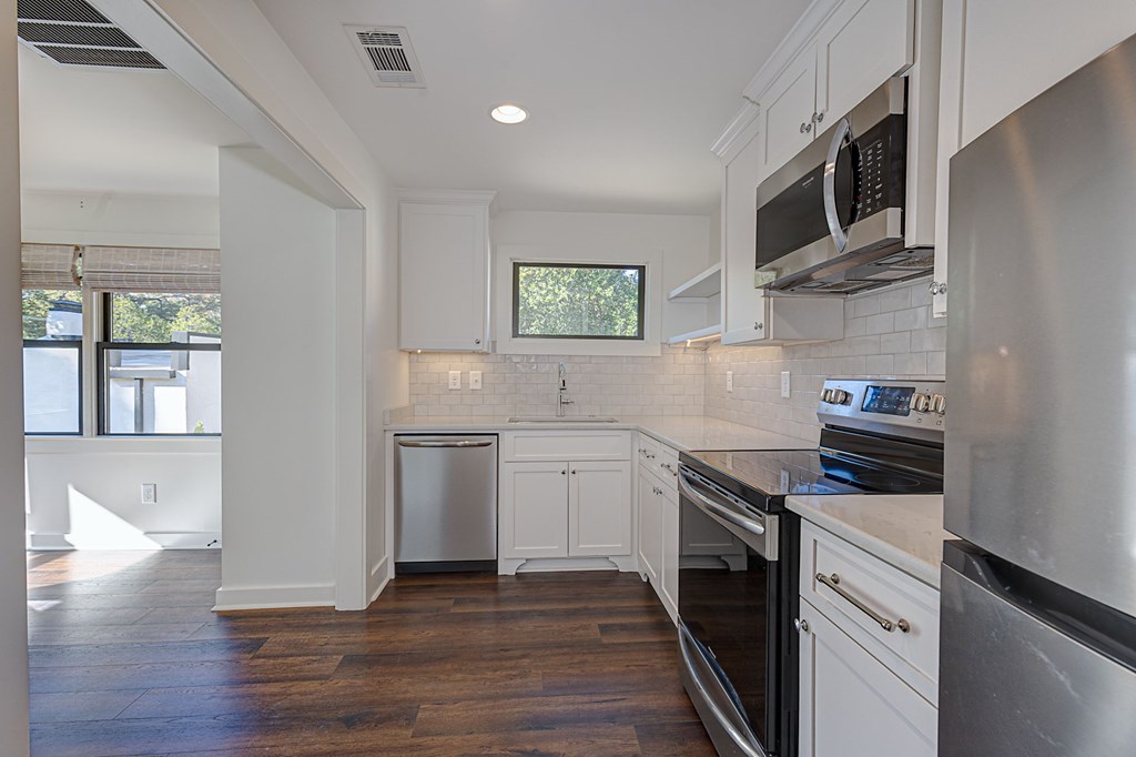 1400 17th Avenue Columbus, GA 31901 - Photo 41 of 50 a kitchen with stainless steel appliances granite countertop a stove top oven a sink dishwasher and white cabinets with wooden floor