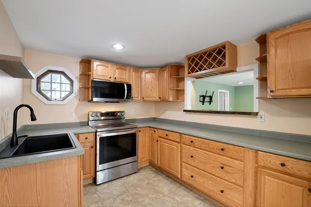 a kitchen with granite countertop stainless steel appliances a sink cabinets and a window