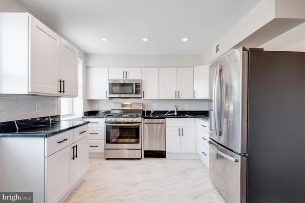a kitchen with granite countertop white cabinets and stainless steel appliances