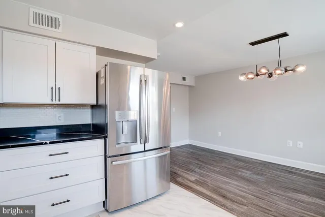 a kitchen with granite countertop a refrigerator and cabinets
