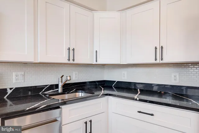 a kitchen with granite countertop white cabinets and a sink