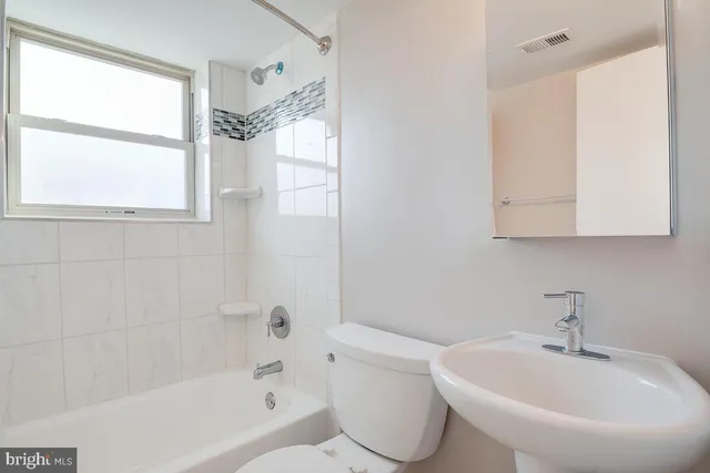 a white bath tub sitting next to a white sink and a toilet
