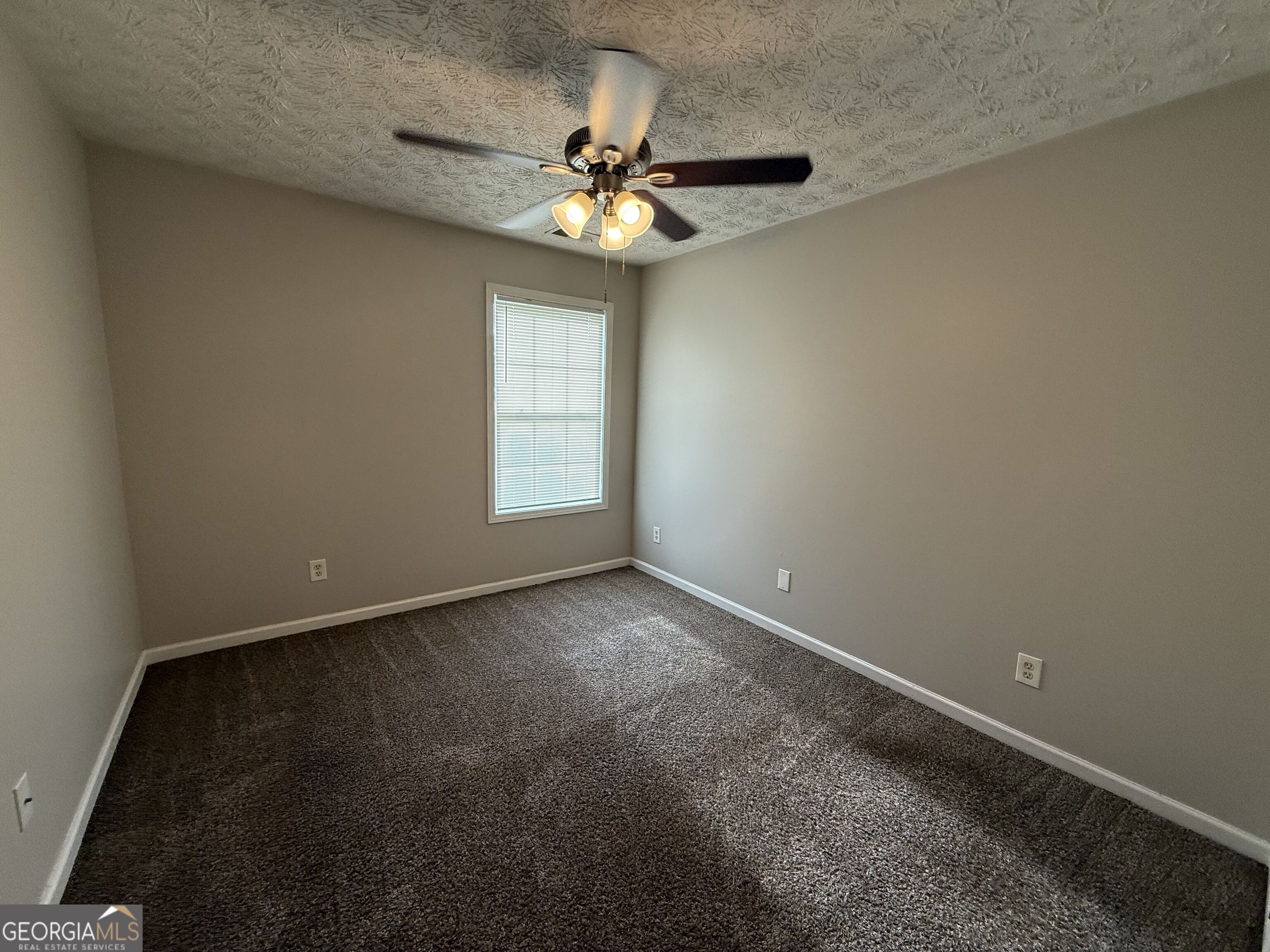 6132 Ruth Street Southwest Covington, GA 30014 - Photo 20 of 33 an empty room with a chandelier fan and windows