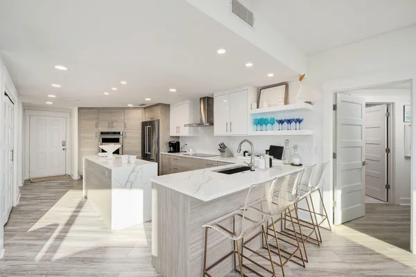 a living room with stainless steel appliances furniture a dining table and a chandelier