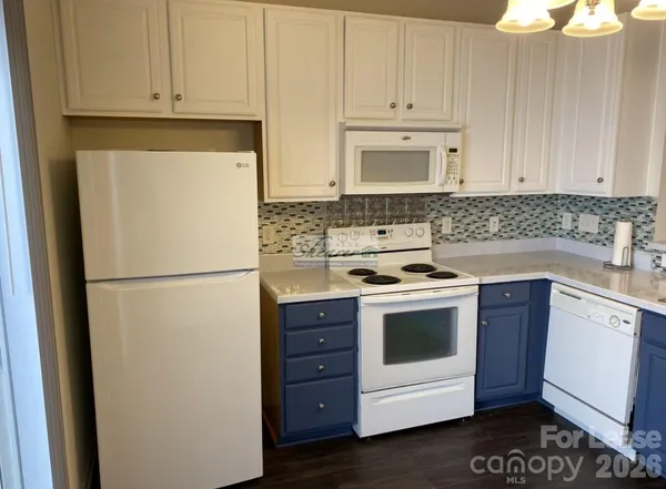 a kitchen with a stove white cabinets and white appliances