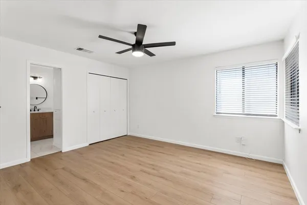 an empty room with wooden floor a ceiling fan and windows