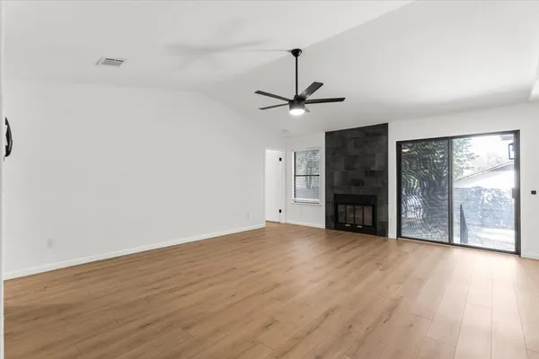 a view of an empty room with a window and wooden floor