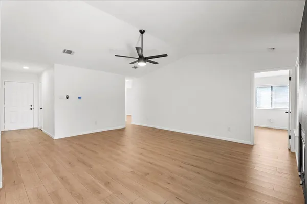 a view of a room with wooden floor and a ceiling fan