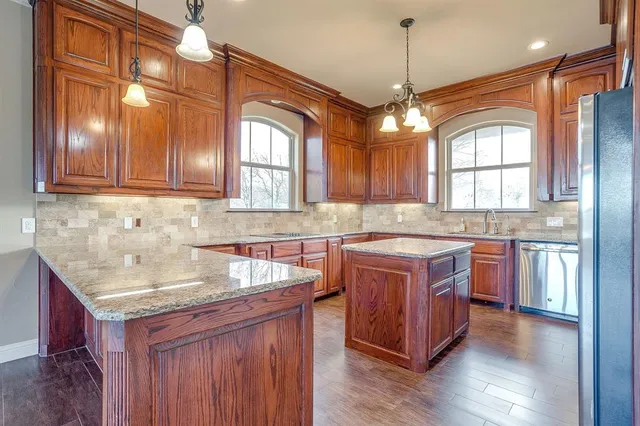 a kitchen with stainless steel appliances granite countertop wooden floors and wooden cabinets