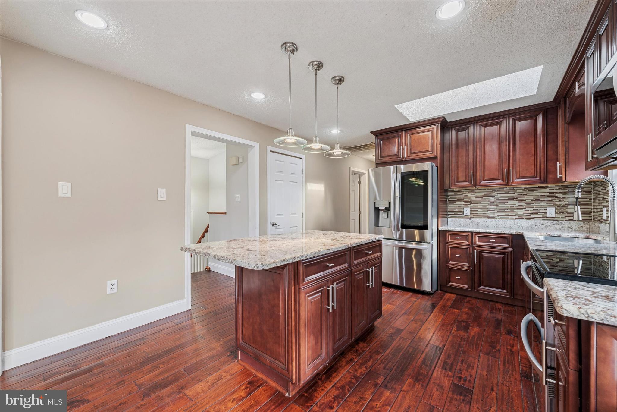 1430 South Bailey Road Coatesville, PA 19320 - Photo 3 of 37 a kitchen with granite countertop a stove a sink wooden floor and kitchen island