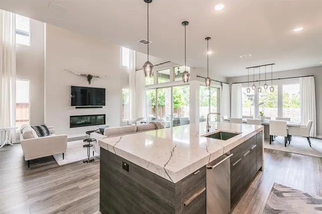 a living room with stainless steel appliances granite countertop a sink a counter space and living room view