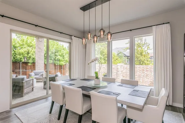 a dining room with wooden floor a chandelier a glass table and chairs