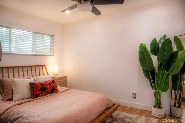 a bedroom with a bed a potted plant and a window