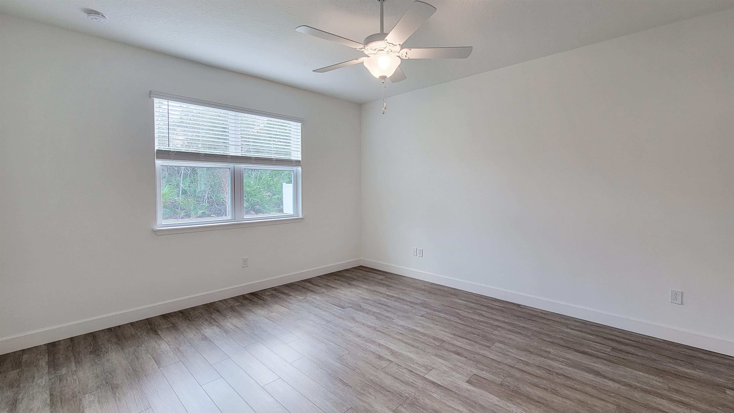 62 Roxboro Drive Palm Coast, FL 32164 - Photo 19 of 35 an empty room with wooden floor ceiling fan and windows