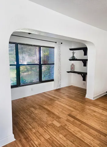 a view of empty room with wooden floor and window