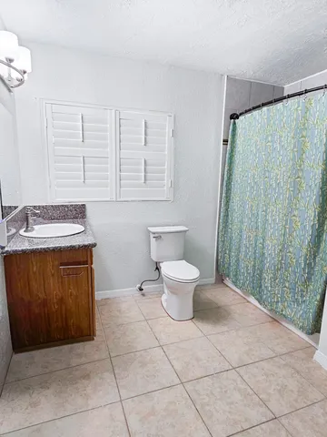 a spacious bathroom with a granite countertop sink a toilet and a mirror