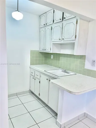 a kitchen with a sink a stove cabinets and utility