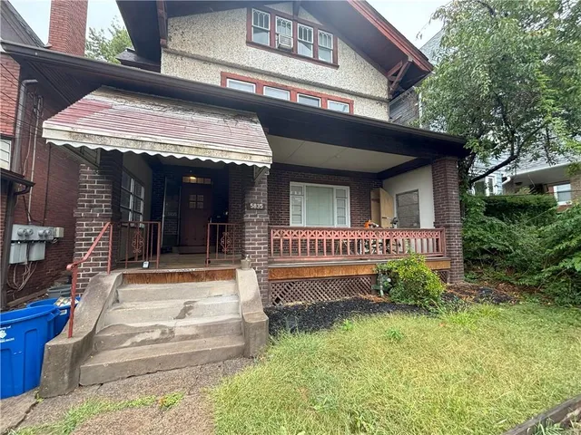 a view of a house with a small yard plants and large tree