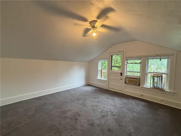 an empty room with windows and ceiling fan