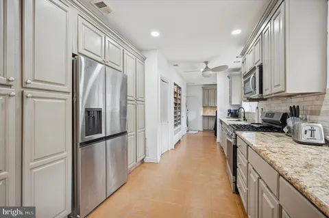 a kitchen with stainless steel appliances granite countertop a refrigerator a stove and a sink with wooden floor