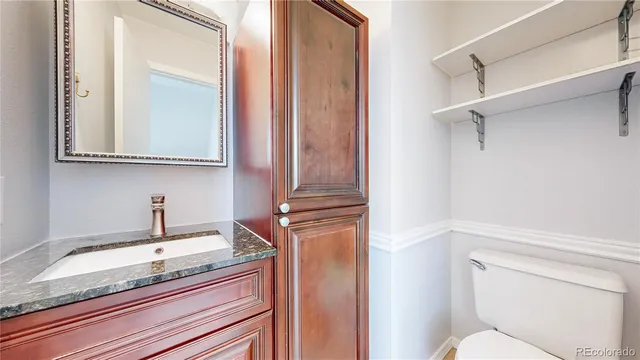 a bathroom with a granite countertop sink and a toilet