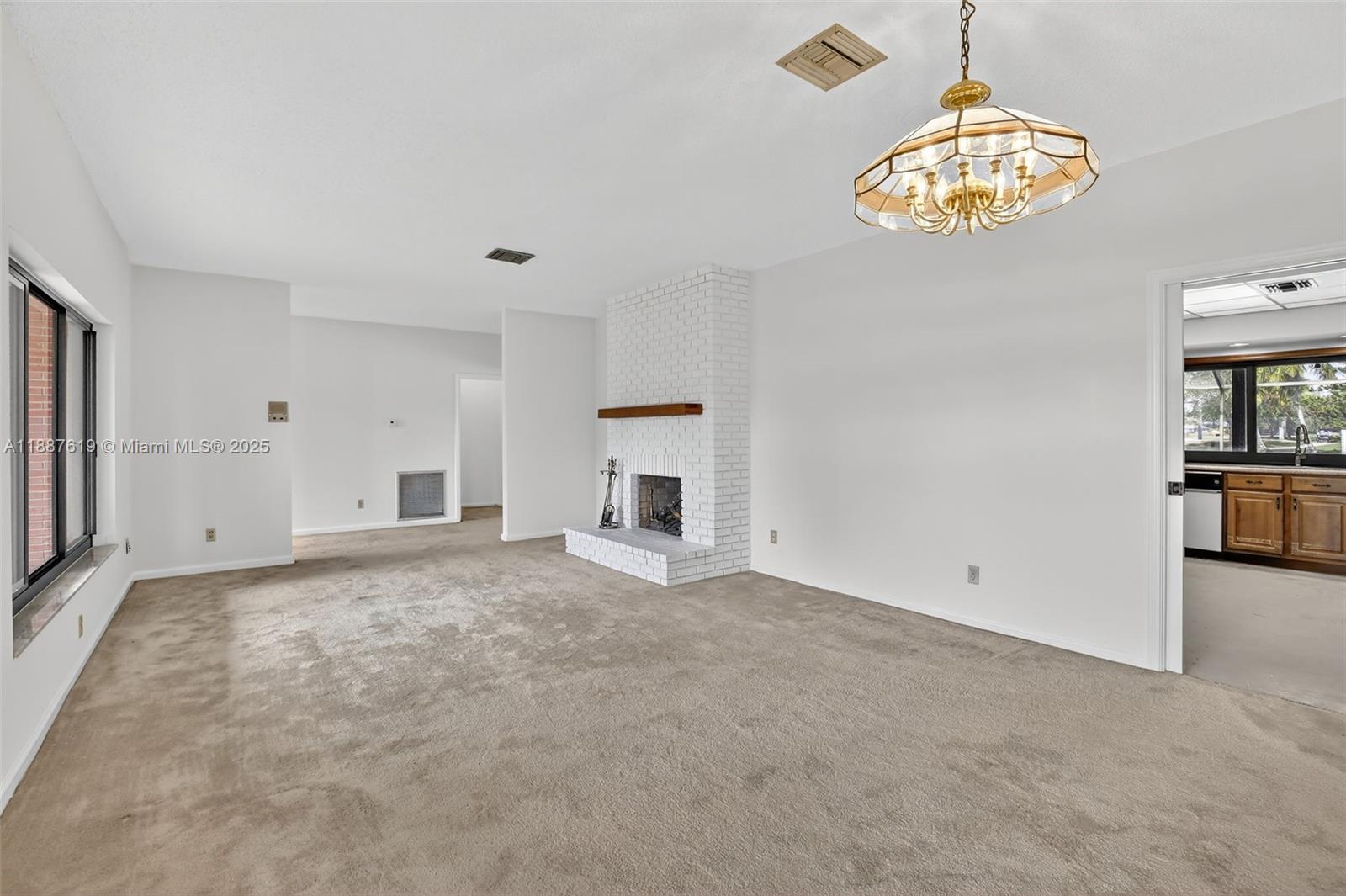 100 129th Avenue Plantation, FL 33325 - Photo 14 of 60 an empty room with a fireplace and chandelier