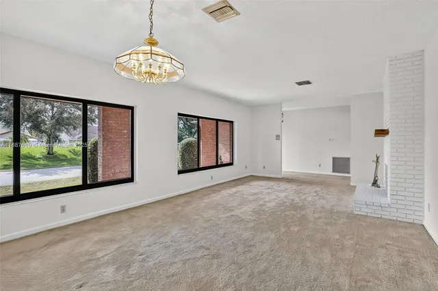 a view of an empty room with a fireplace and a ceiling fan