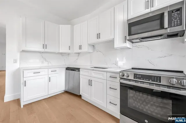 a kitchen with cabinets stainless steel appliances and sink