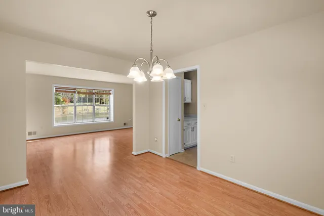 a view of a room with wooden floor chandelier and windows