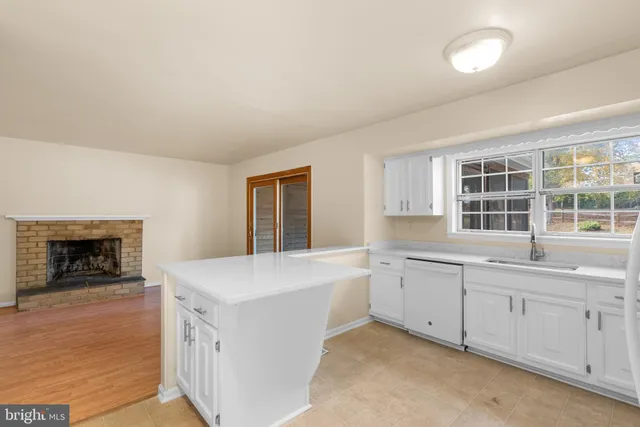 a view of a kitchen with a sink a fireplace and window