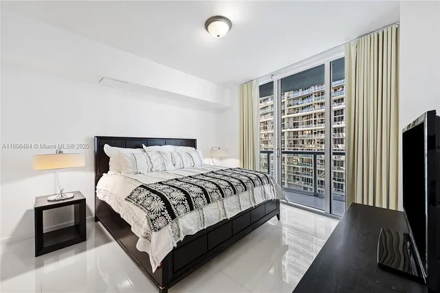 a bedroom with a bed and a flat tv screen next to a window