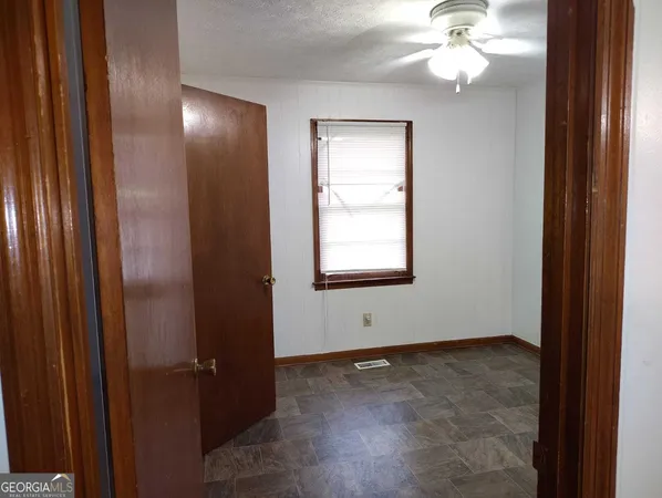 an empty room with windows and fan