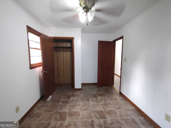 an empty room with wooden floor chandelier fan and windows