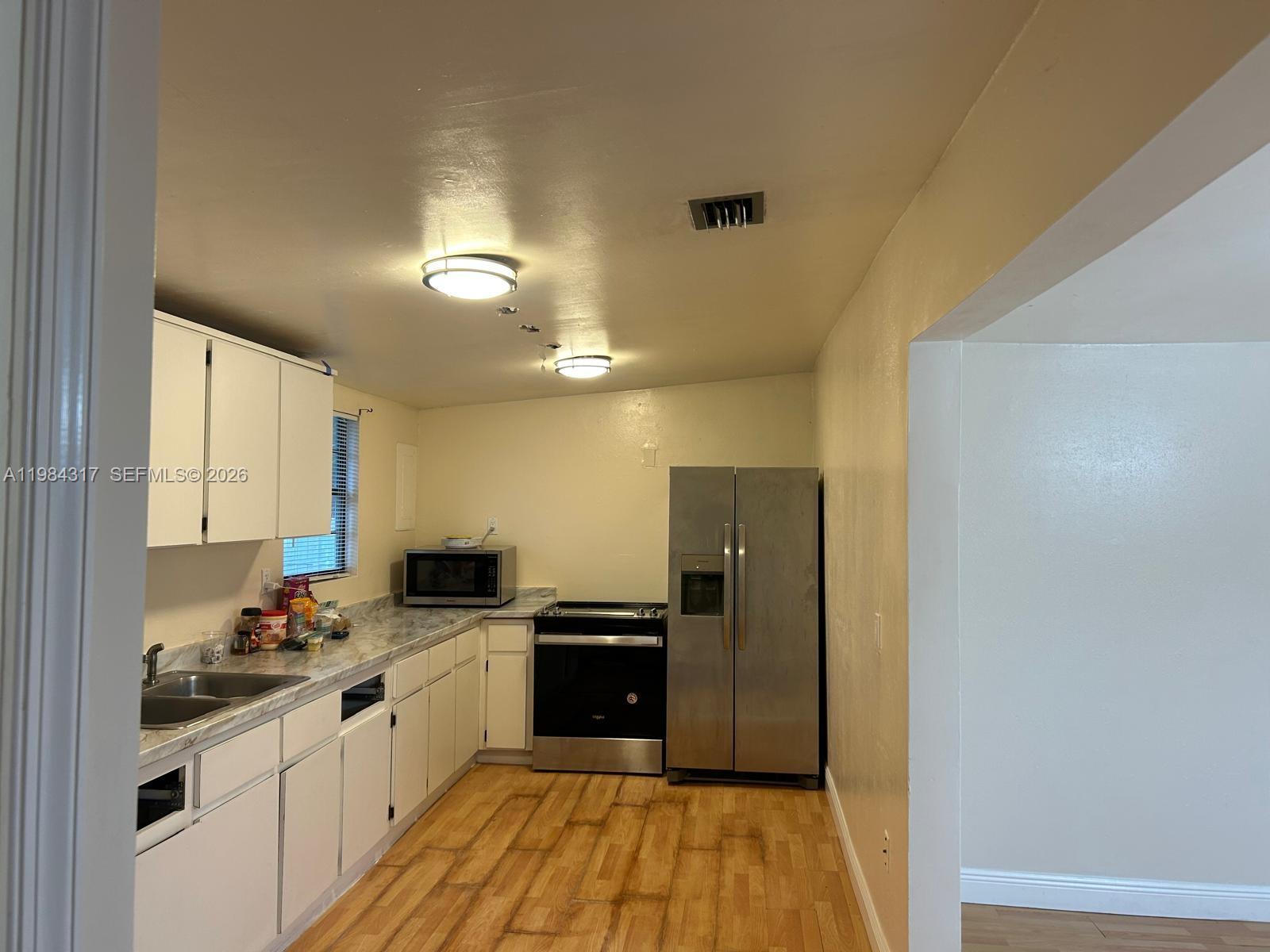 8866 Southwest 126th Street Miami, FL 33176 - Photo 17 of 20 a kitchen with granite countertop a refrigerator a sink a stove and white cabinets