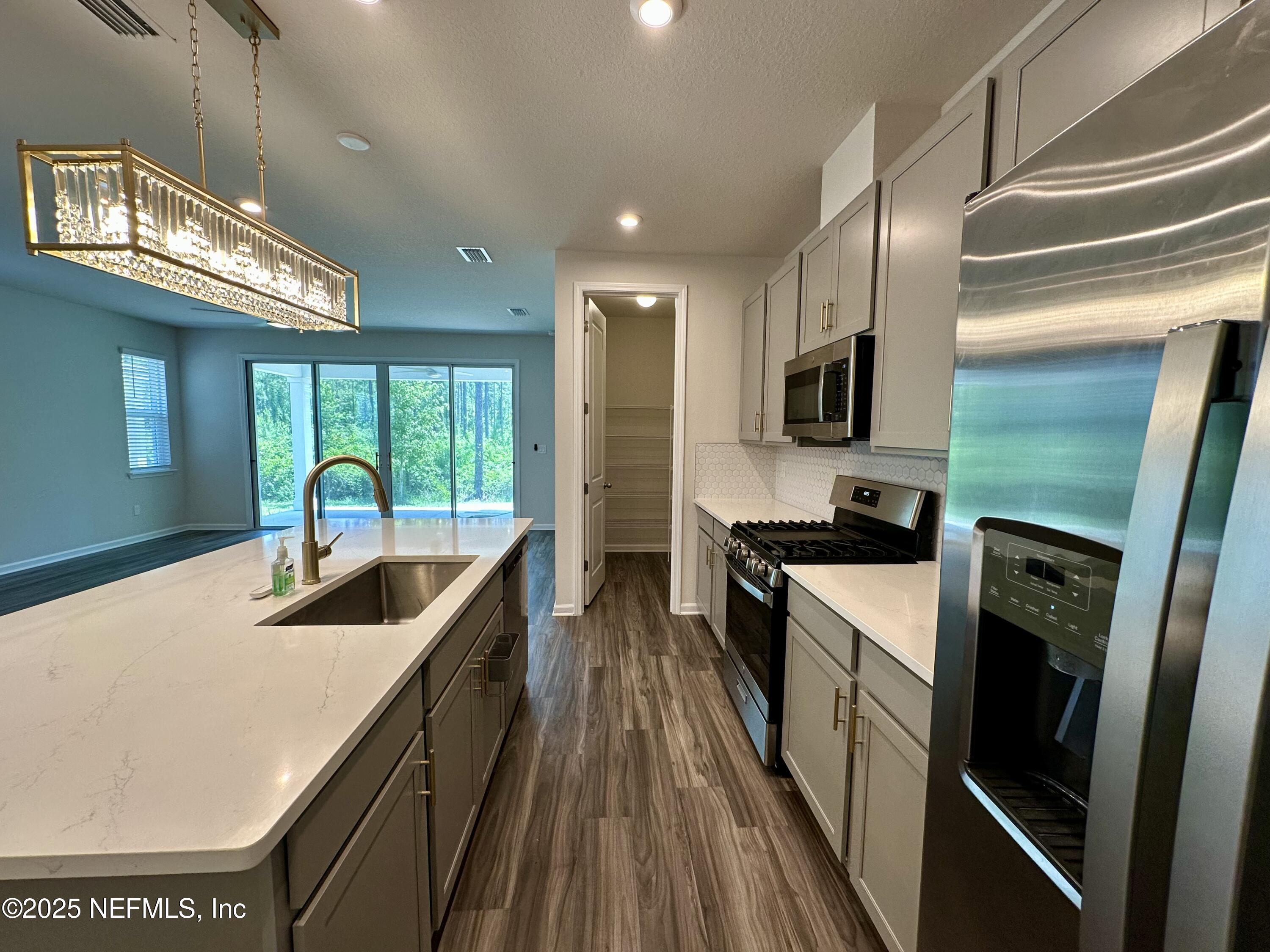75310 White Rabbit Avenue Yulee, FL 32097 - Photo 13 of 61 a kitchen with kitchen island granite countertop a sink a counter top space stainless steel appliances and cabinets
